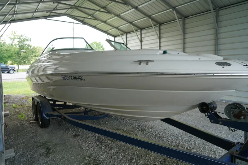 Slide: The Image of 2000 Sea Ray 210 Sundeck boat on trailer under metal shelter. - 5