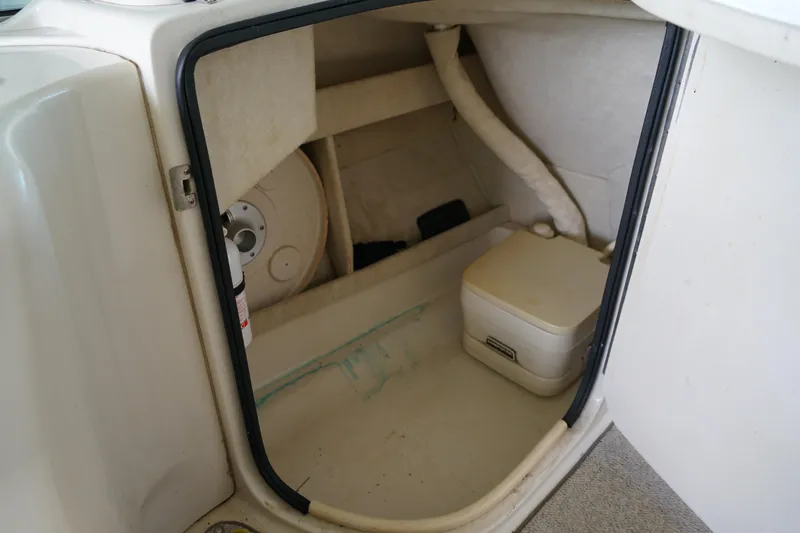 Slide: The Image of Storage compartment inside a 2000 Sea Ray 210 Sundeck boat, featuring a portable toilet. - 14