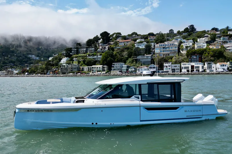 Slide: The Image of 2027 Saxdor 400 GTC boat cruising near scenic coastal town with hillside houses. - 4