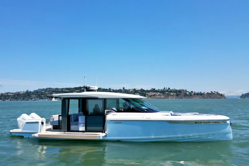 Slide: The Image of 2027 Saxdor 400 GTC boat cruising on a sunny day with scenic coastline backdrop. - 10