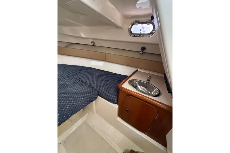 Slide: The Image of 2006 Pursuit 2570 Offshore cabin interior with bed and compact sink area. - 16
