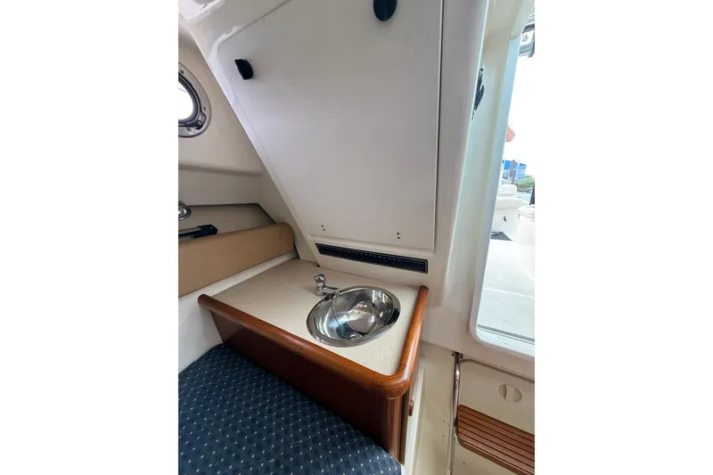 Slide: The Image of 2006 Pursuit 2570 Offshore cabin interior with sink and seating area. - 17
