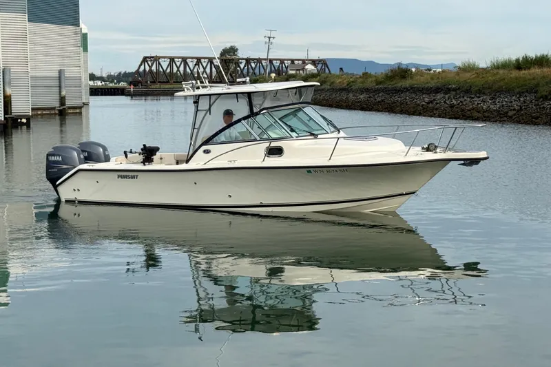 Slide: The Image of 2006 Pursuit 2570 Offshore boat on calm water near a dock and bridge. - 24