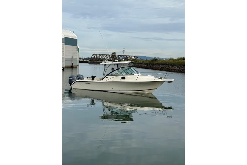 Slide: The Image of 2006 Pursuit 2570 Offshore boat on calm water near a dock and bridge. - 25