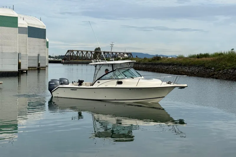 Slide: The Image of 2006 Pursuit 2570 Offshore boat on calm water near docks and bridge. - 26