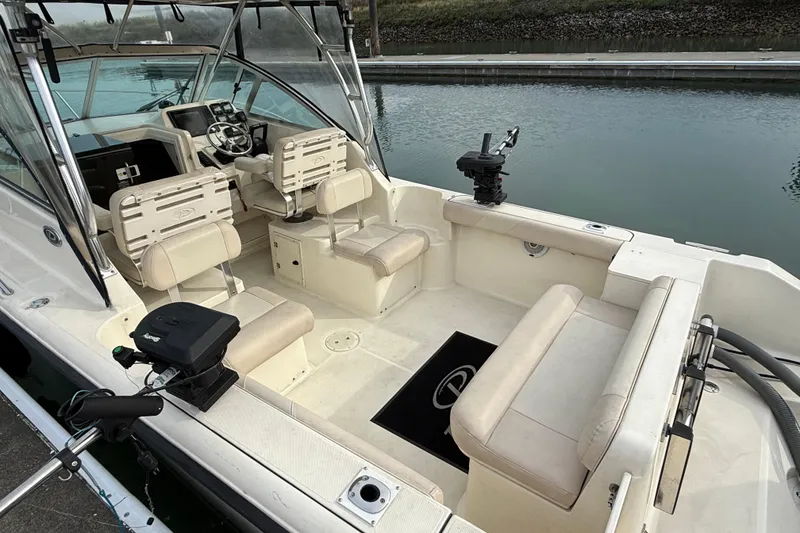 Slide: The Image of 2006 Pursuit 2570 Offshore boat interior with seating and steering wheel, docked by calm water. - 4