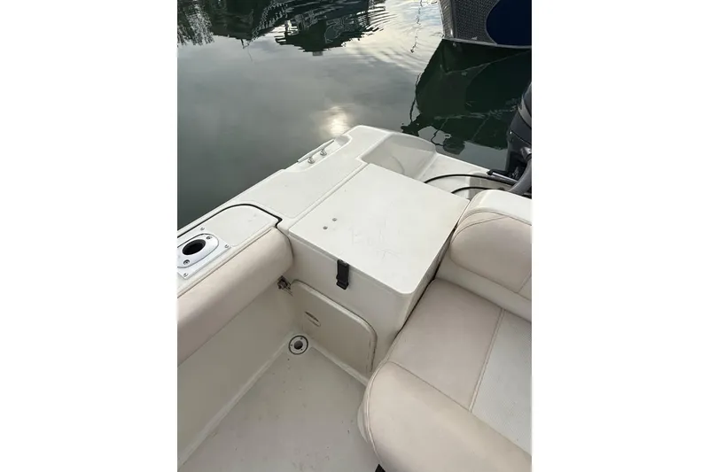 Slide: The Image of 2006 Pursuit 2570 Offshore boat interior with seating and storage, docked on calm water. - 6