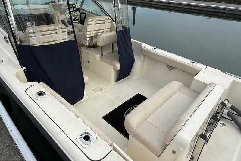 Slide: The Image of 2006 Pursuit 2570 Offshore boat interior with seating and steering area, docked by calm water. - 7
