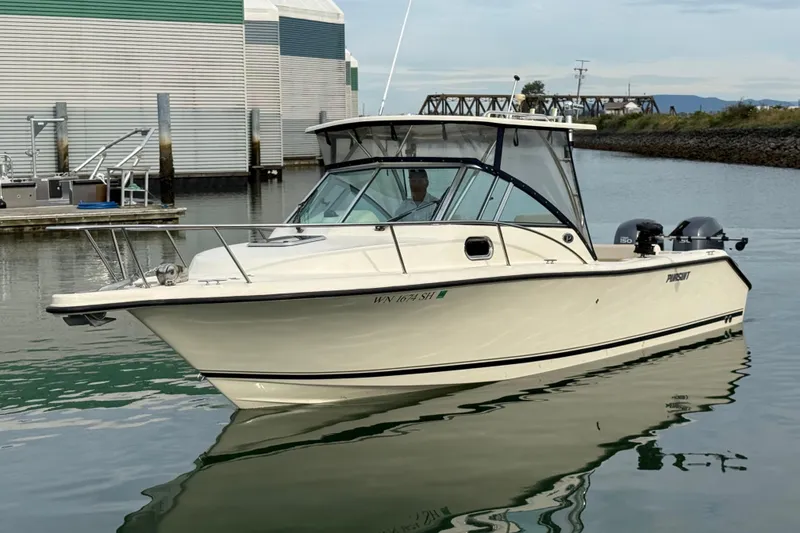 The Image of 2006 Pursuit 2570 Offshore boat docked in calm waters near a marina. - 0