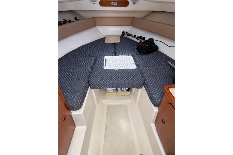 Slide: The Image of 2007 Pursuit 2570 Offshore cabin interior with cushioned seating and storage. - 40