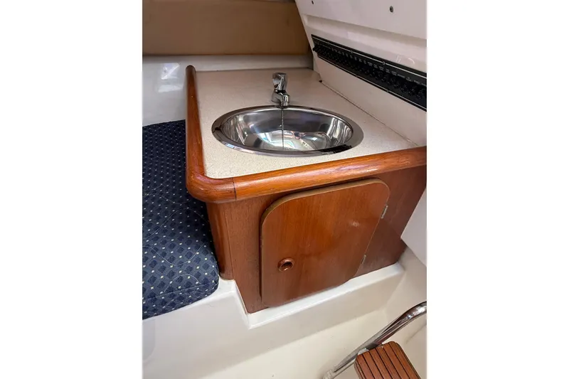 Slide: The Image of 2007 Pursuit 2570 Offshore boat interior with sink and wooden cabinet. - 44