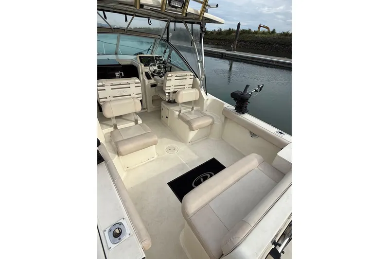 Slide: The Image of 2006 Pursuit 2570 Offshore boat interior with seating and steering wheel, docked by calm water. - 22