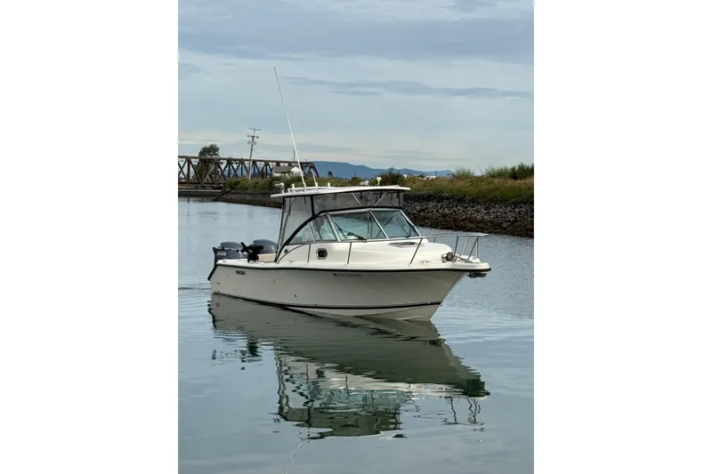 Slide: The Image of 2006 Pursuit 2570 Offshore boat on calm water, near a bridge and shoreline. - 27