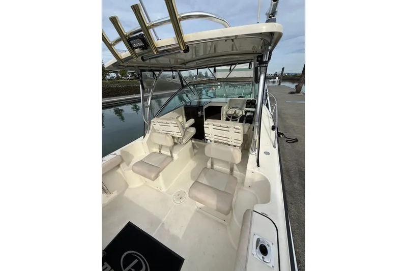 Slide: The Image of 2006 Pursuit 2570 Offshore boat interior with seating and helm, docked by calm water. - 28