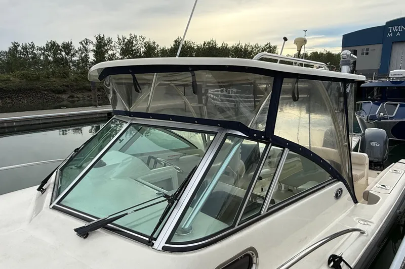 Slide: The Image of 2006 Pursuit 2570 Offshore boat docked, featuring a clear windshield and canopy. - 29