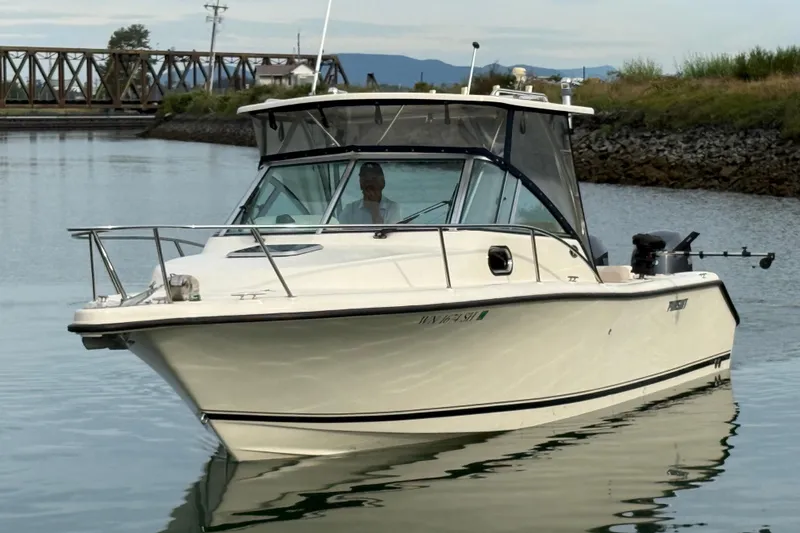 Slide: The Image of 2006 Pursuit 2570 Offshore boat cruising on calm water near a bridge. - 35