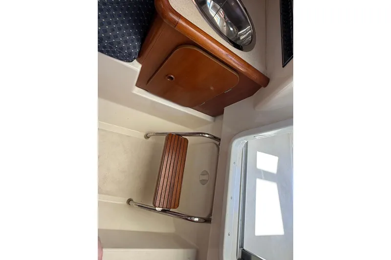 Slide: The Image of 2007 Pursuit 2570 Offshore cabin interior with wooden seat and storage. - 43