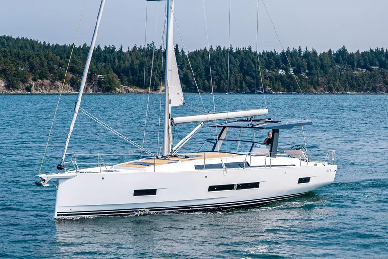 Slide: The Image of 2025 Hanse 460 yacht sailing on a serene blue sea near a forested coastline. - 2