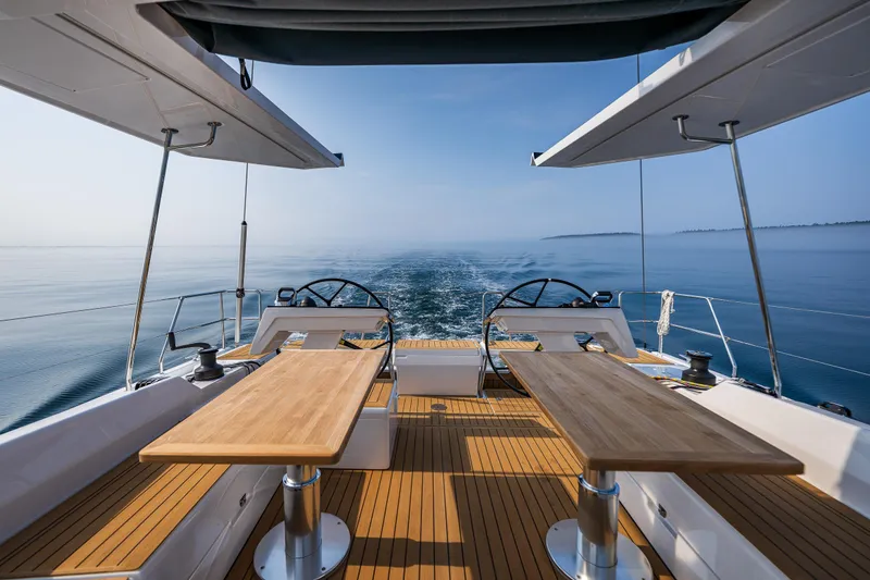 Slide: The Image of Luxurious 2025 Hanse 460 yacht deck with dual steering wheels and wooden tables, cruising on calm waters. - 7