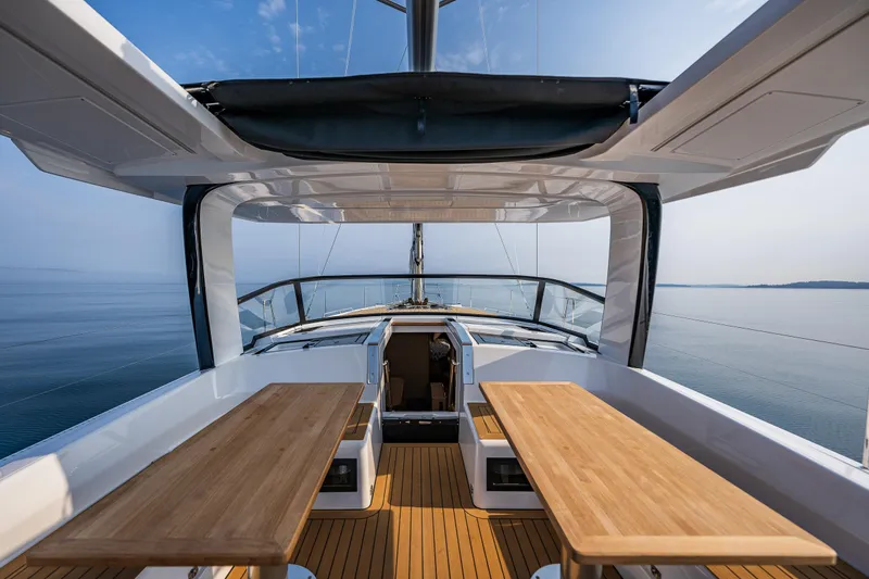 Slide: The Image of 2025 Hanse 460 yacht deck with wooden tables, overlooking calm sea and clear sky. - 6