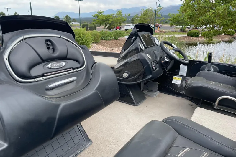 Slide: The Image of 2016 Nitro Z21 boat interior with steering wheel and seating, parked near a pond. - 3