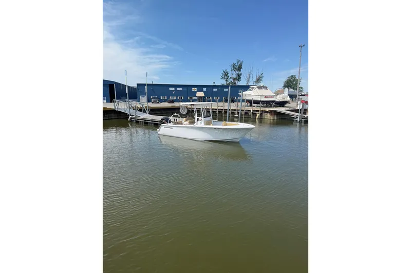 Slide: The Image of 2023 Sportsman Open 232 Center Console boat docked at a marina under clear blue skies. - 25
