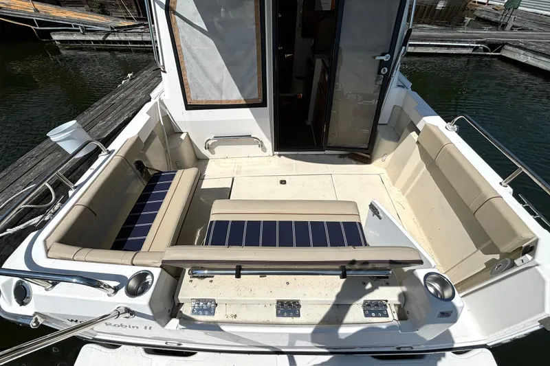 Slide: The Image of 2021 Ranger Tugs R-25 boat cockpit with beige seating and open cabin door. - 20