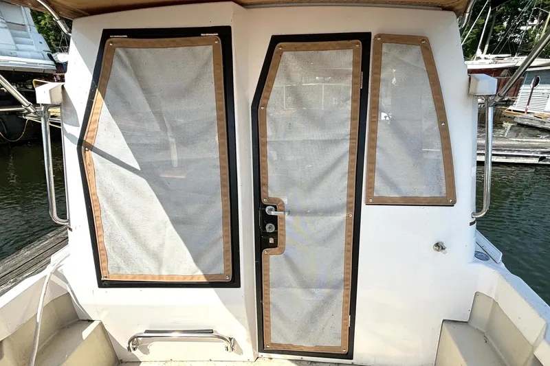 Slide: The Image of 2021 Ranger Tugs R-25 boat cabin door with mesh coverings, docked at marina. - 25