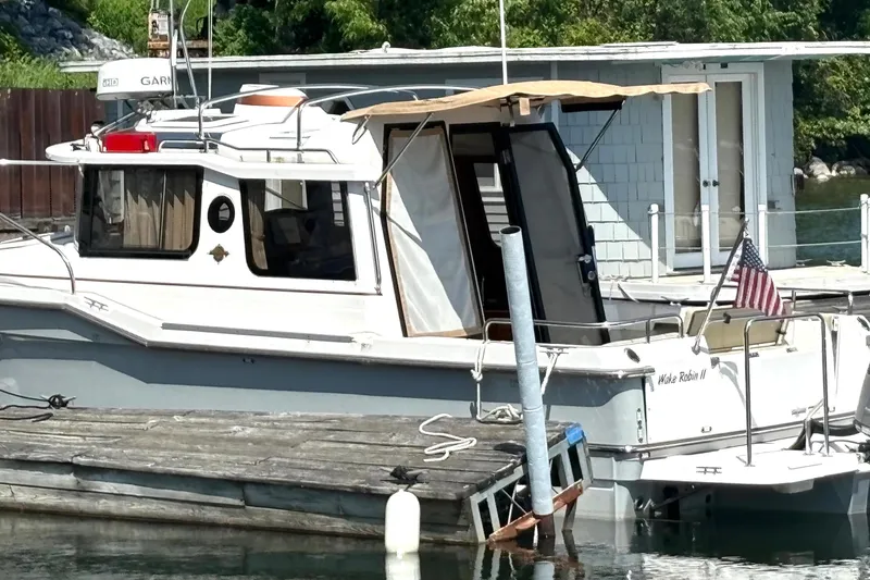Slide: The Image of 2021 Ranger Tugs R-25 boat docked, featuring an American flag and canopy. - 7