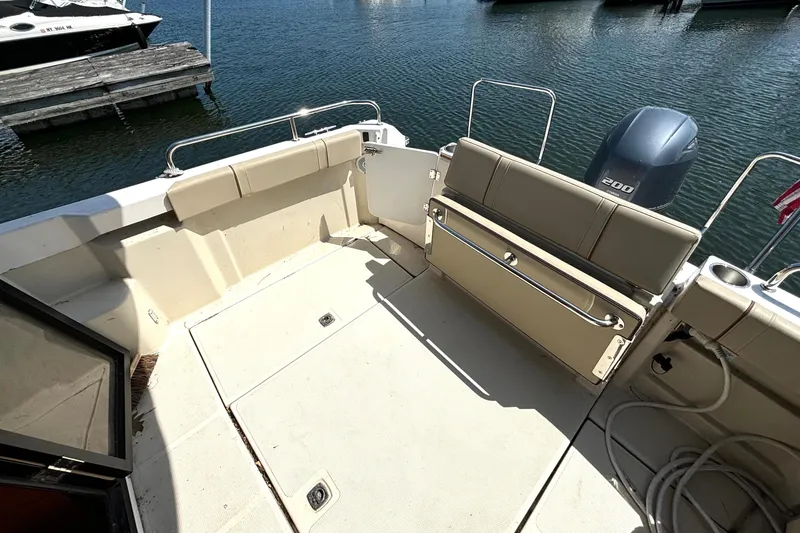 Slide: The Image of 2021 Ranger Tugs R-25 boat deck with seating and outboard motor at marina. - 12