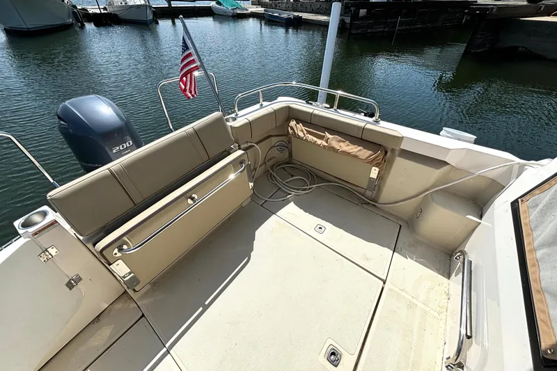 Slide: The Image of 2021 Ranger Tugs R-25 boat deck with seating and outboard motor in marina. - 13