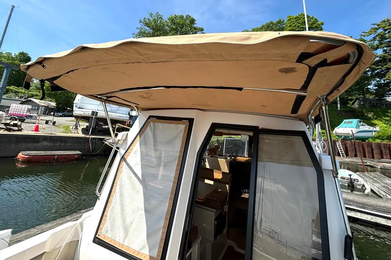 Slide: The Image of 2021 Ranger Tugs R-25 boat with canopy docked at marina under clear blue sky. - 24