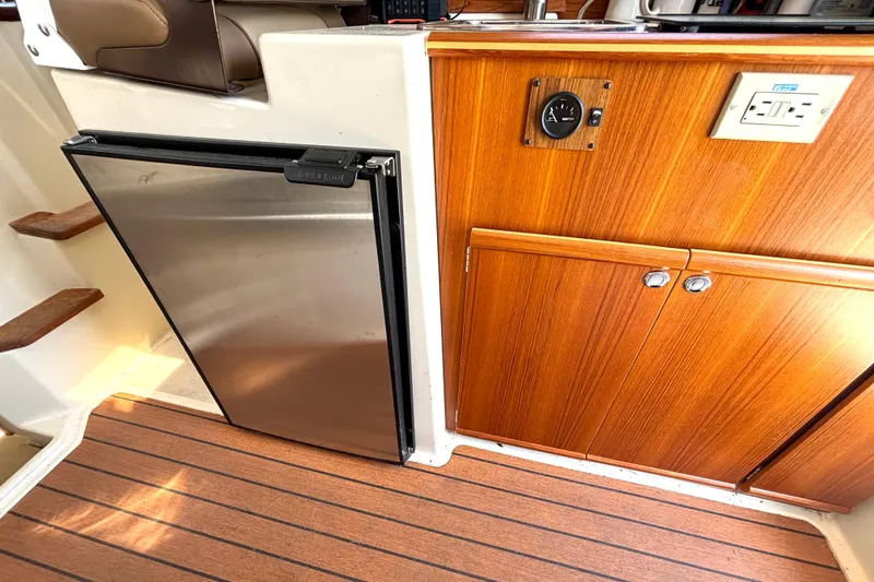Slide: The Image of Interior of 2021 Ranger Tugs R-25 with stainless steel fridge and wooden cabinetry. - 40