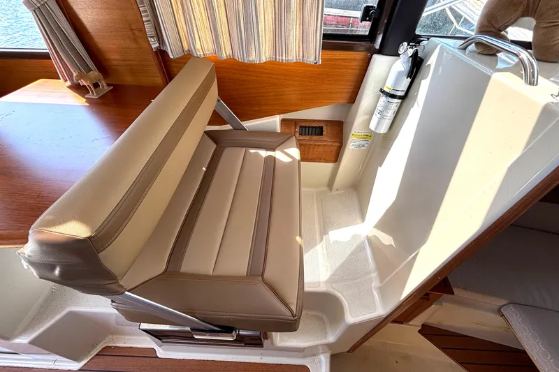 Slide: The Image of 2021 Ranger Tugs R-25 interior seating with beige upholstery and wooden accents. - 44
