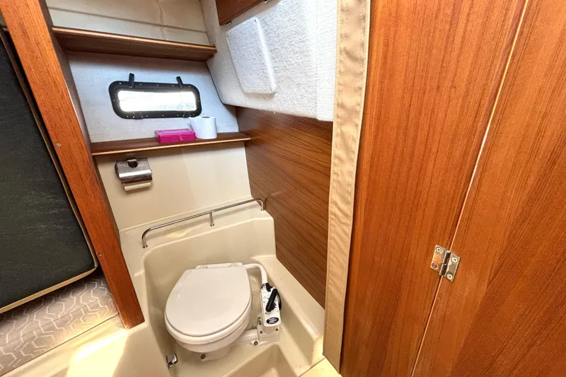 Slide: The Image of 2021 Ranger Tugs R-25 boat bathroom with wooden accents and compact toilet. - 52