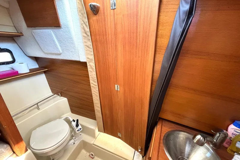 Slide: The Image of 2021 Ranger Tugs R-25 boat bathroom with wooden interior, toilet, and sink. - 53
