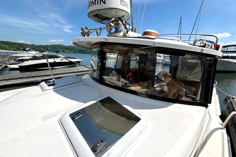 Slide: The Image of 2021 Ranger Tugs R-25 boat docked, with a dog inside the cabin, under clear skies. - 9