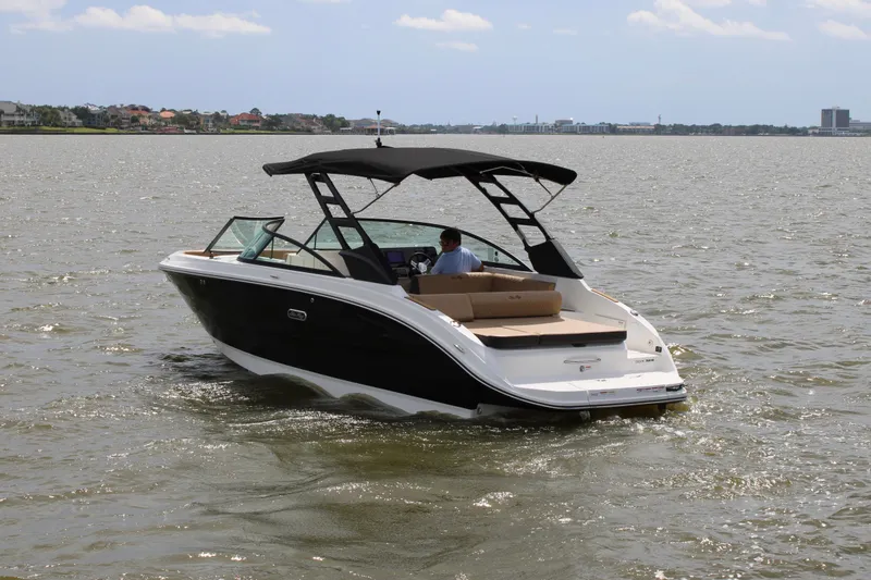 Slide: The Image of 2026 Sea Ray SDX 250 Surf on calm water with black canopy and beige interior. - 1