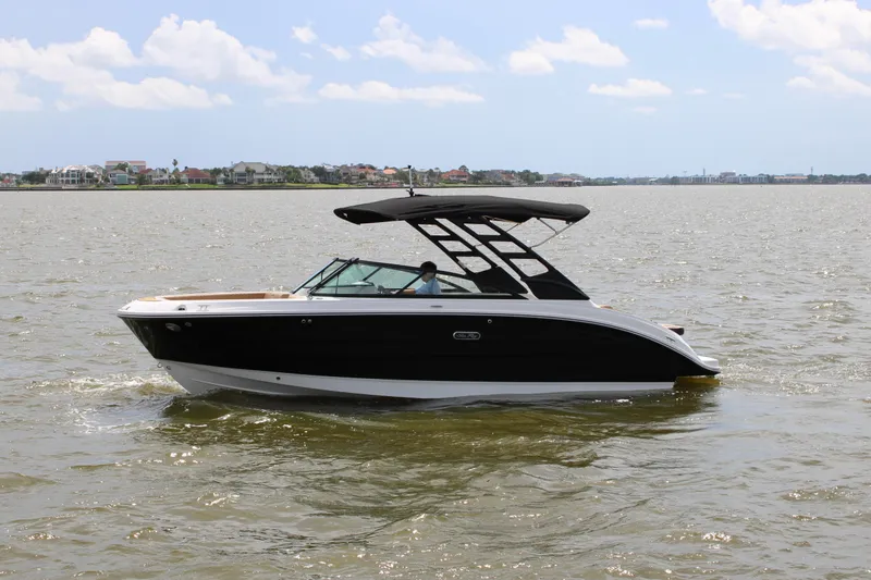 Slide: The Image of A 2026 Sea Ray SDX 250 Surf cruising on calm waters, featuring a sleek black hull. - 0