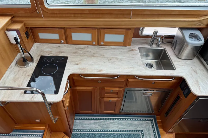 Slide: The Image of 2019 Sabre 45 Salon Express yacht kitchen with stove, sink, and wooden cabinetry. - 28