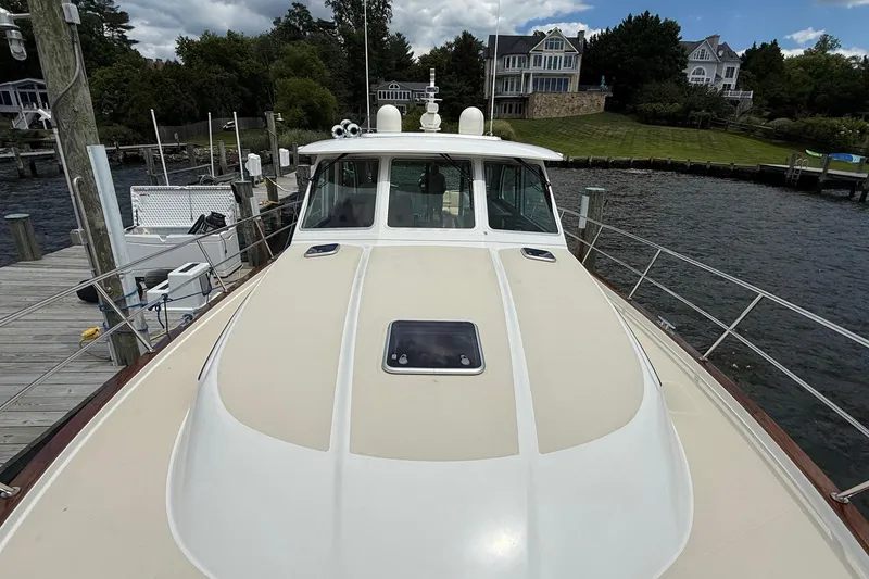 Slide: The Image of 2019 Sabre 45 Salon Express yacht docked by waterfront homes, showcasing sleek design and spacious deck. - 3