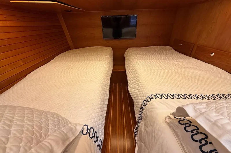 Slide: The Image of Twin beds in the 2019 Sabre 45 Salon Express cabin with wood paneling and TV. - 36