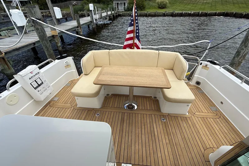 Slide: The Image of 2019 Sabre 45 Salon Express yacht deck with seating, table, and American flag. - 8