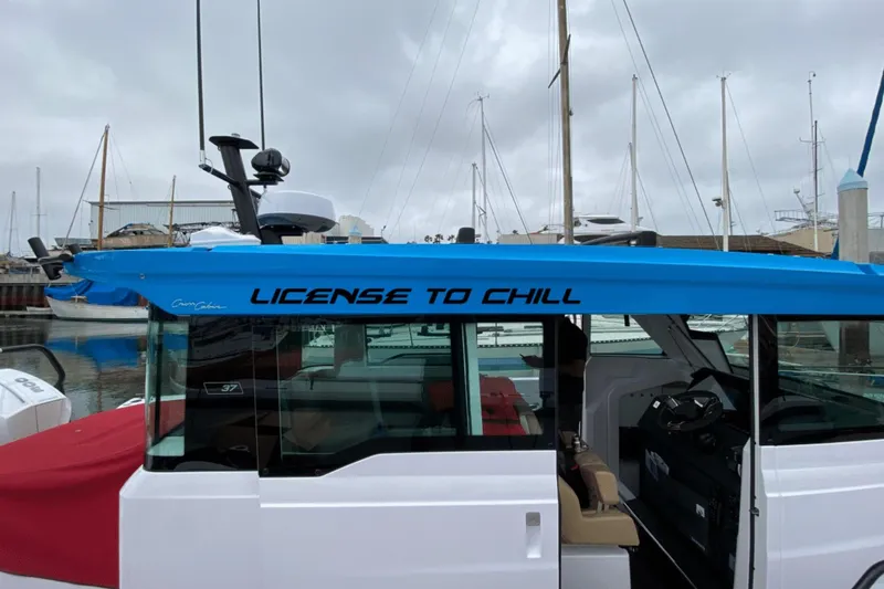Slide: The Image of 2023 Axopar boat with "License to Chill" text, featuring gull-wing doors, docked at marina. - 11
