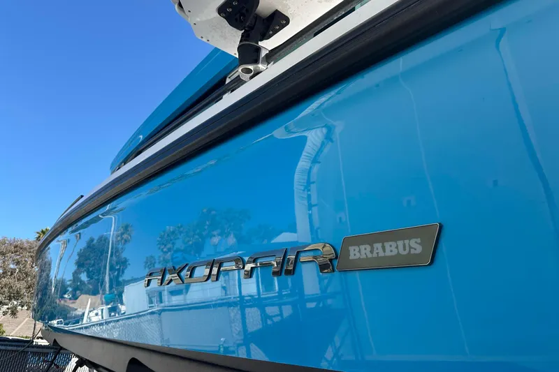 Slide: The Image of 2021 Axopar 37 XC Cross Cabin boat with Brabus branding, blue hull, sunny day. - 2