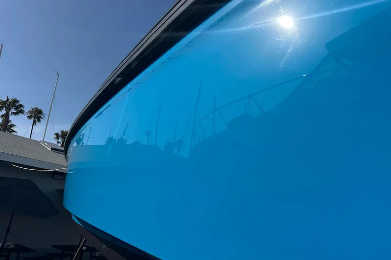 Slide: The Image of 2021 Axopar 37 XC Cross Cabin boat with reflective blue hull under clear sky. - 3