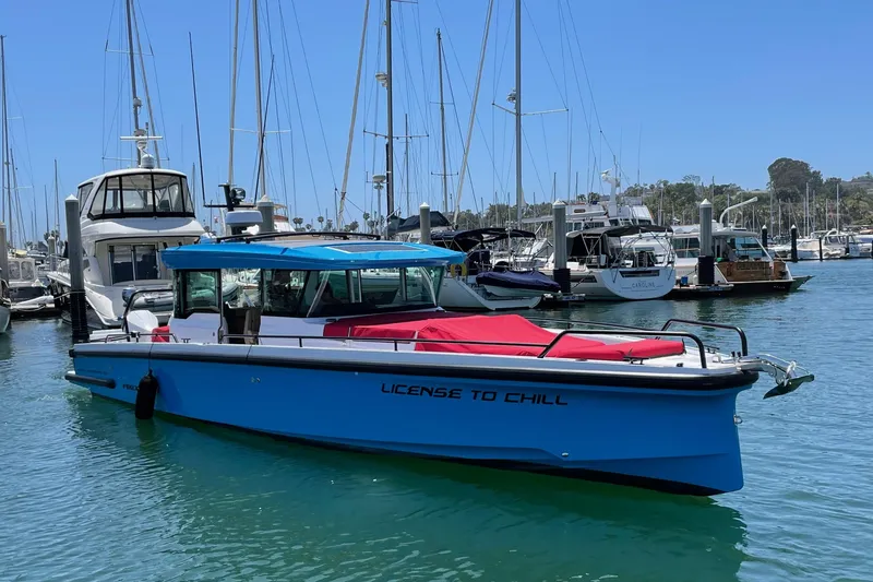 Slide: The Image of 2023 Axopar boat with gull-wing doors, docked in a marina, named "License to Chill". - 4
