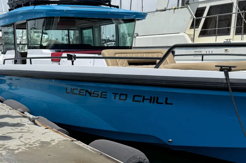 Slide: The Image of 2023 Axopar boat with "License to Chill" text, featuring gull-wing doors, docked at marina. - 5