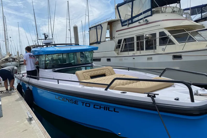 Slide: The Image of 2023 Axopar boat with blue hull, docked, featuring aft cabin and gull-wing doors. - 6