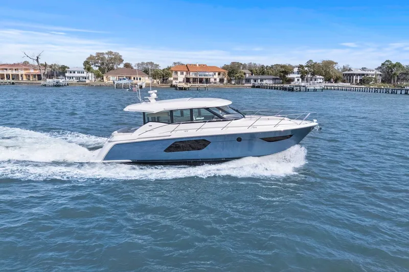 Slide: The Image of 2023 Tiara Yachts C49 Coupe cruising on a scenic waterfront. - 2